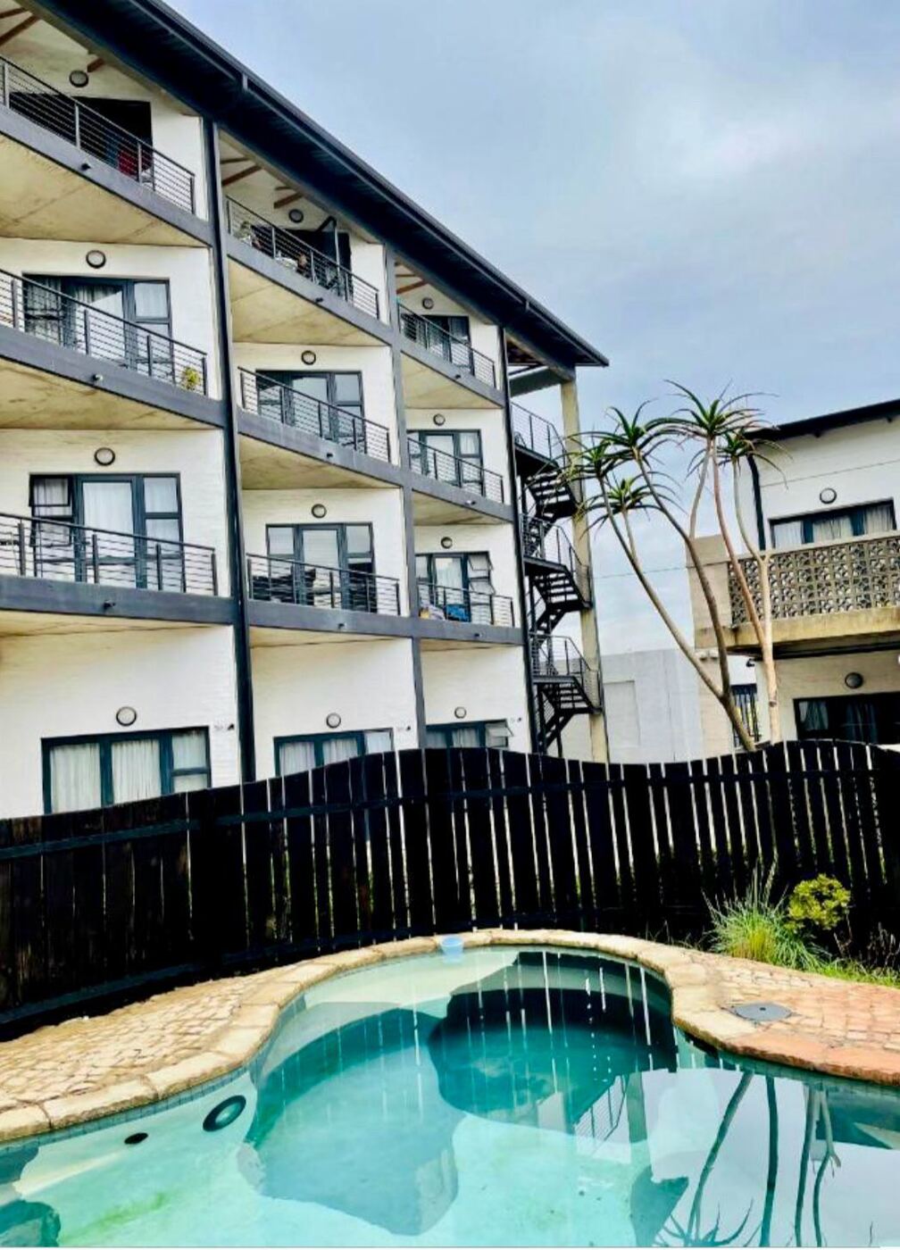 Apartment block with private balconies and a swimming pool, the kind of property Stayease manages