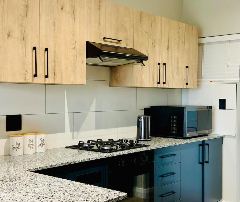 Modern kitchen with light wood cabinets, granite countertops, a gas hob, microwave and navy cabinetry